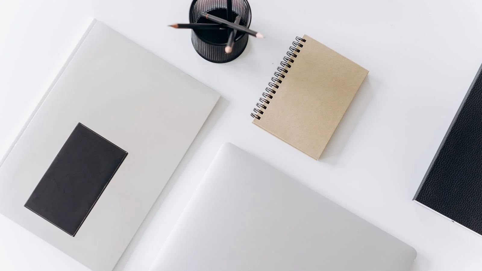 A laptop and notebooks on a white desk, the weekend that produces the asset