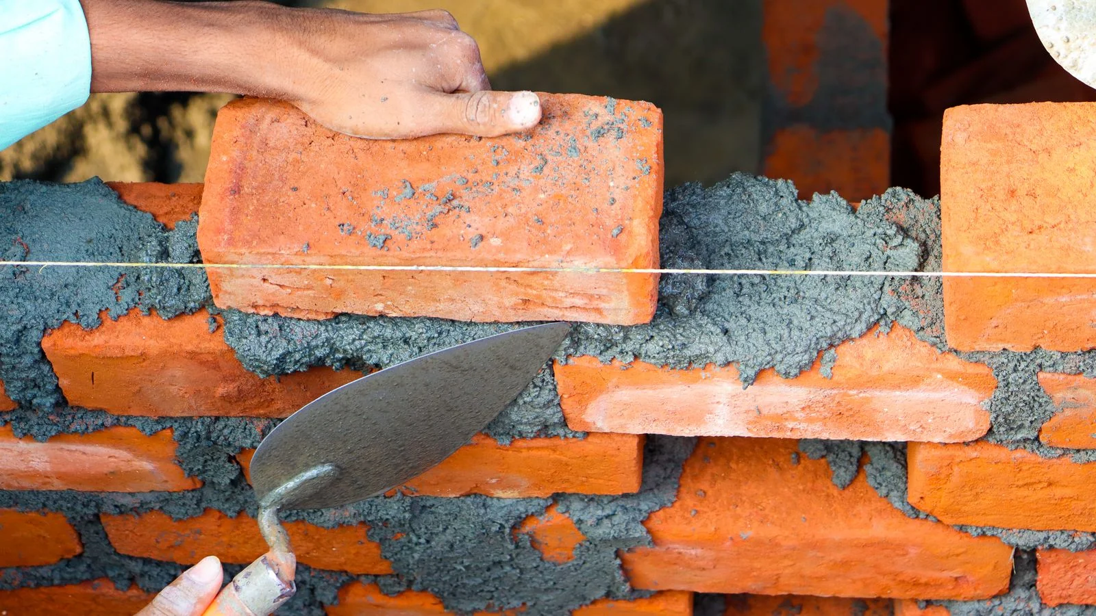 A mason's hands setting brick with cement, the detail work that content has to capture up close.