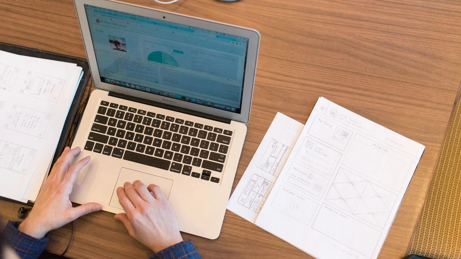 An overhead view of a person working on a laptop at a desk with papers and documents.