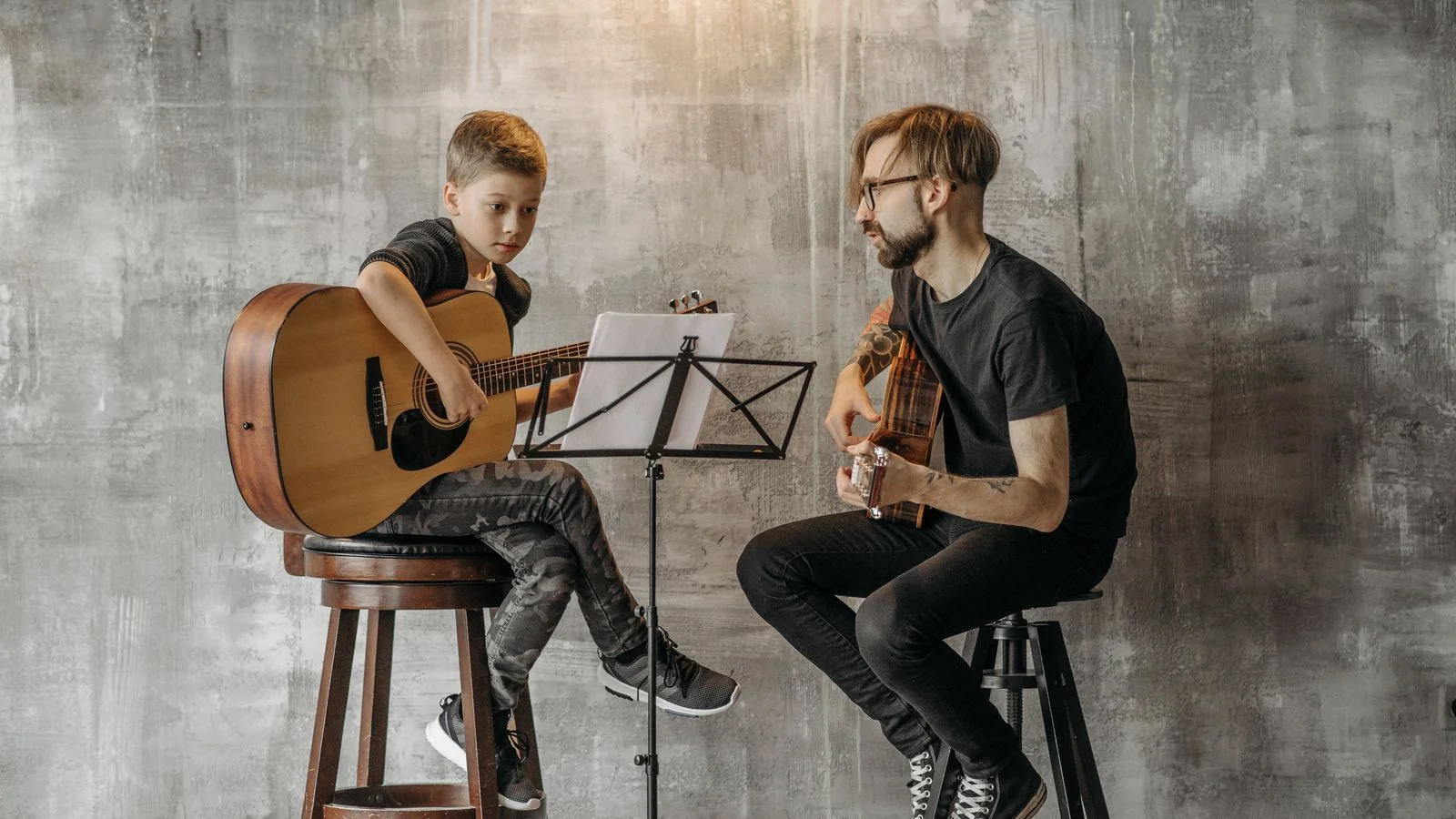 A guitar lesson taking place in a small studio room