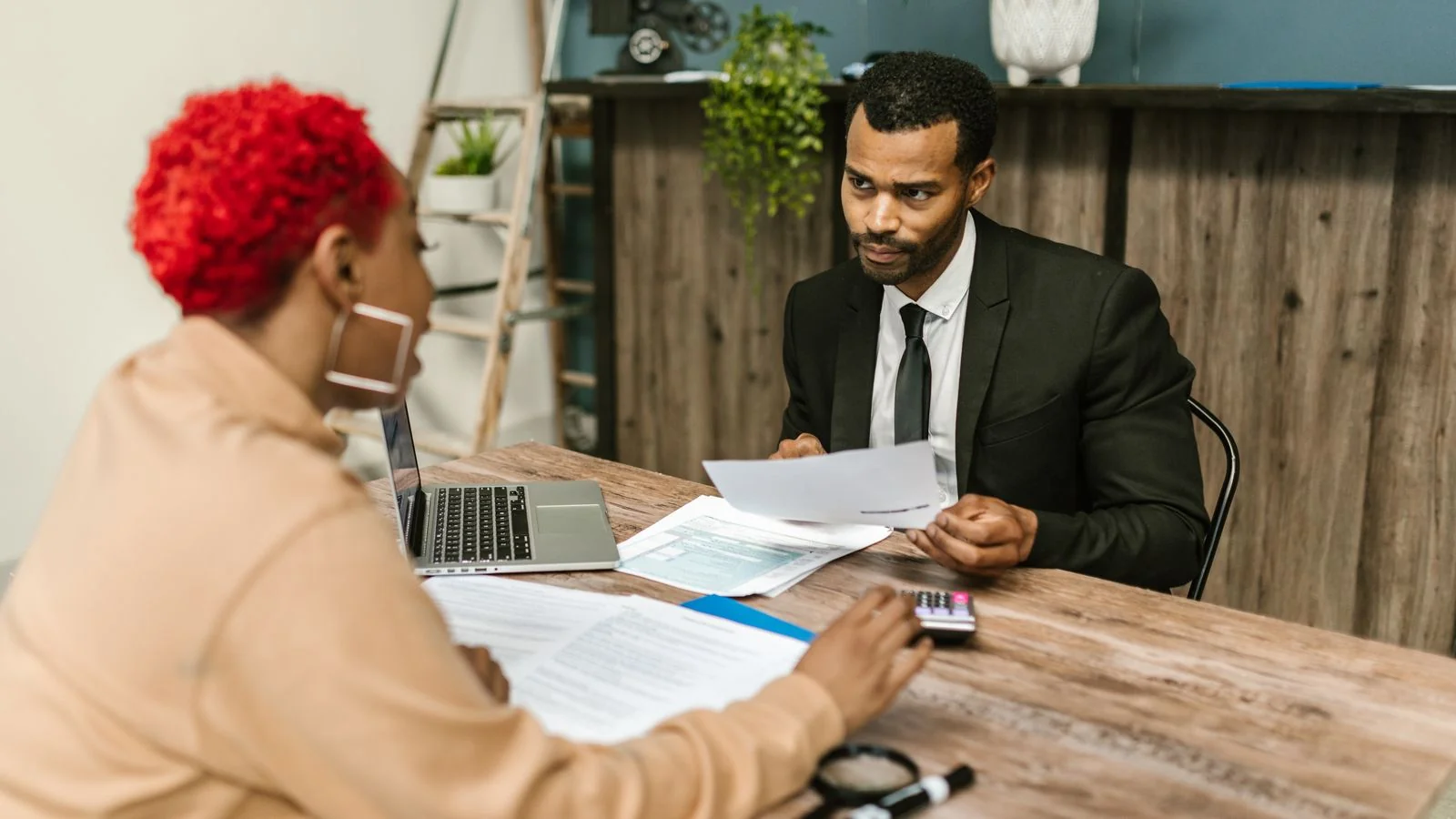Two professionals reviewing financial paperwork together in a modern office.