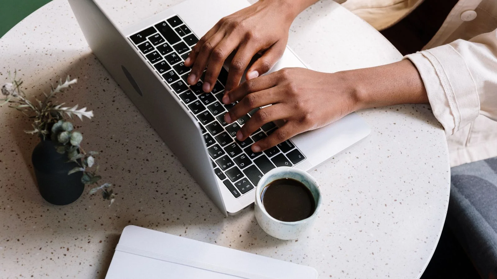 Plumber writing a blog post on a laptop with coffee