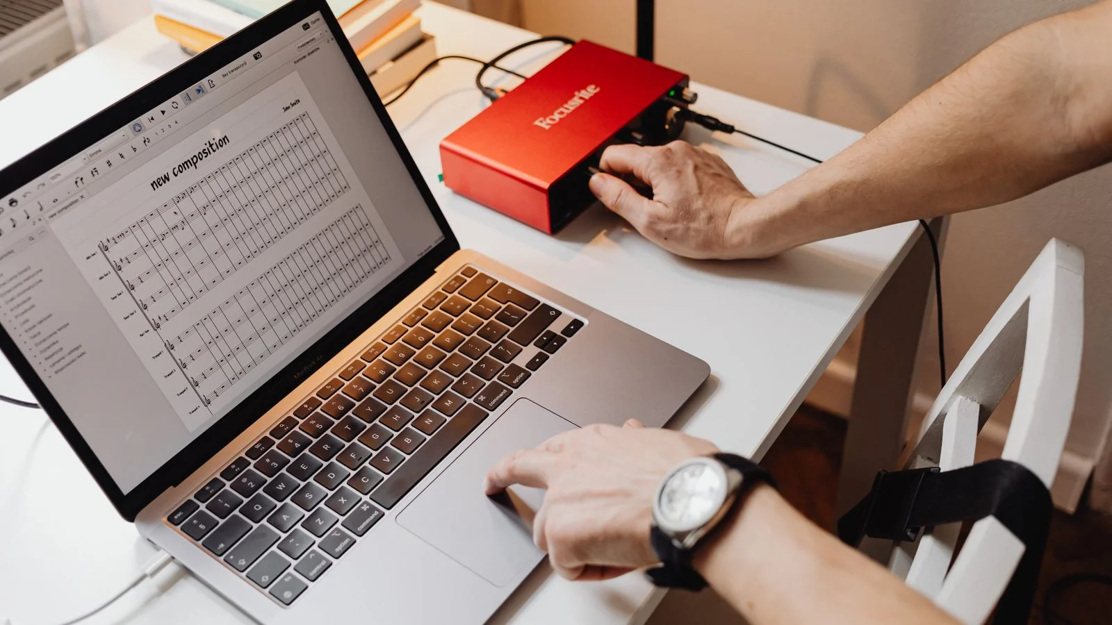 A laptop showing an audio project beside an interface on a desk, the point where a recording becomes source material