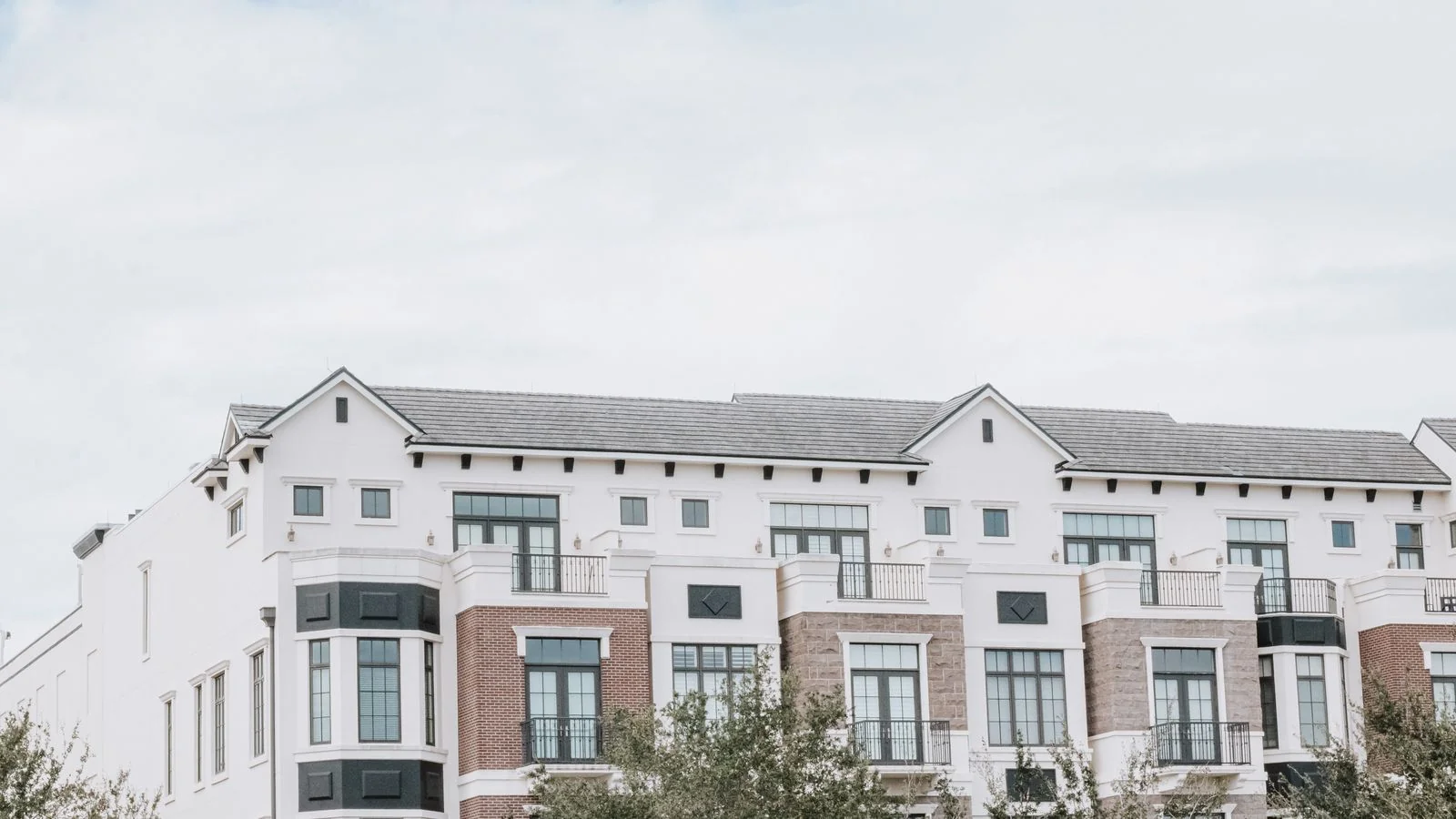 A modern apartment building with a clean white facade, the kind of asset a capital partner will look up before replying to your email.