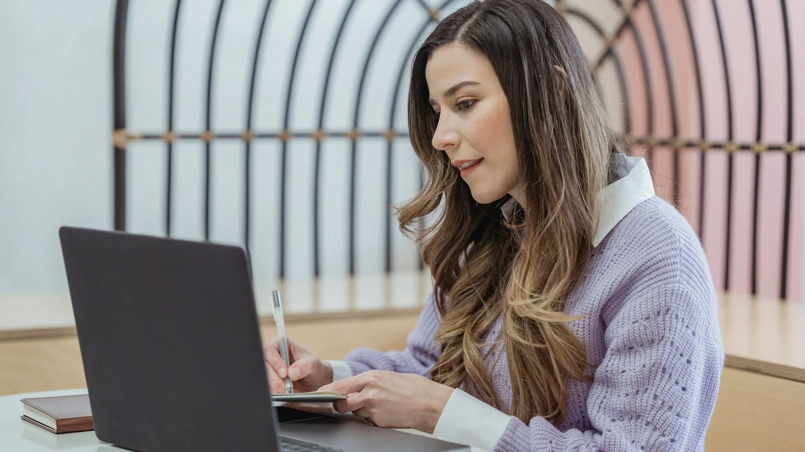 Writer taking notes in a planner beside a laptop, mapping content to the closing calendar.