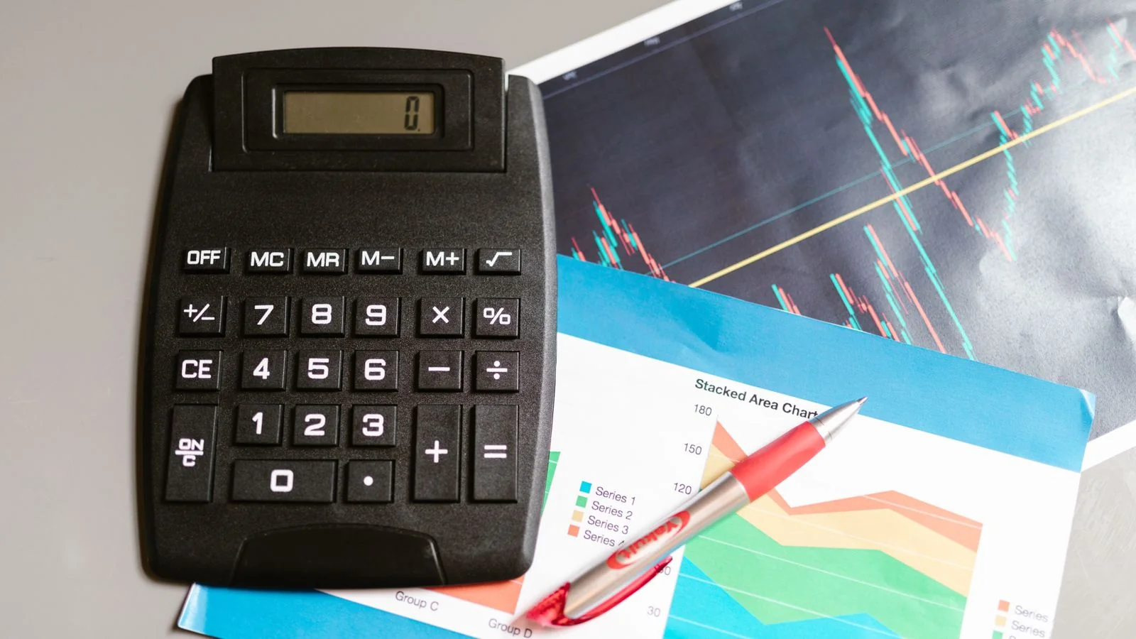 Calculator and pen resting on financial charts, the tools behind a content ROI calculation