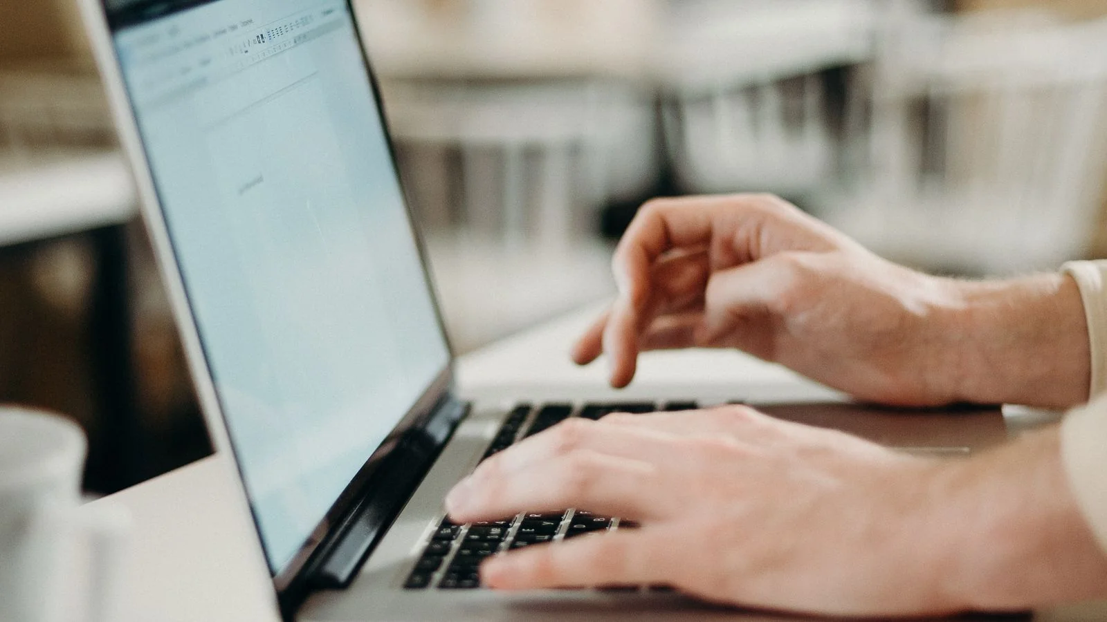 A person typing at a laptop, preparing a release whose opening dateline signals professionalism to reporters