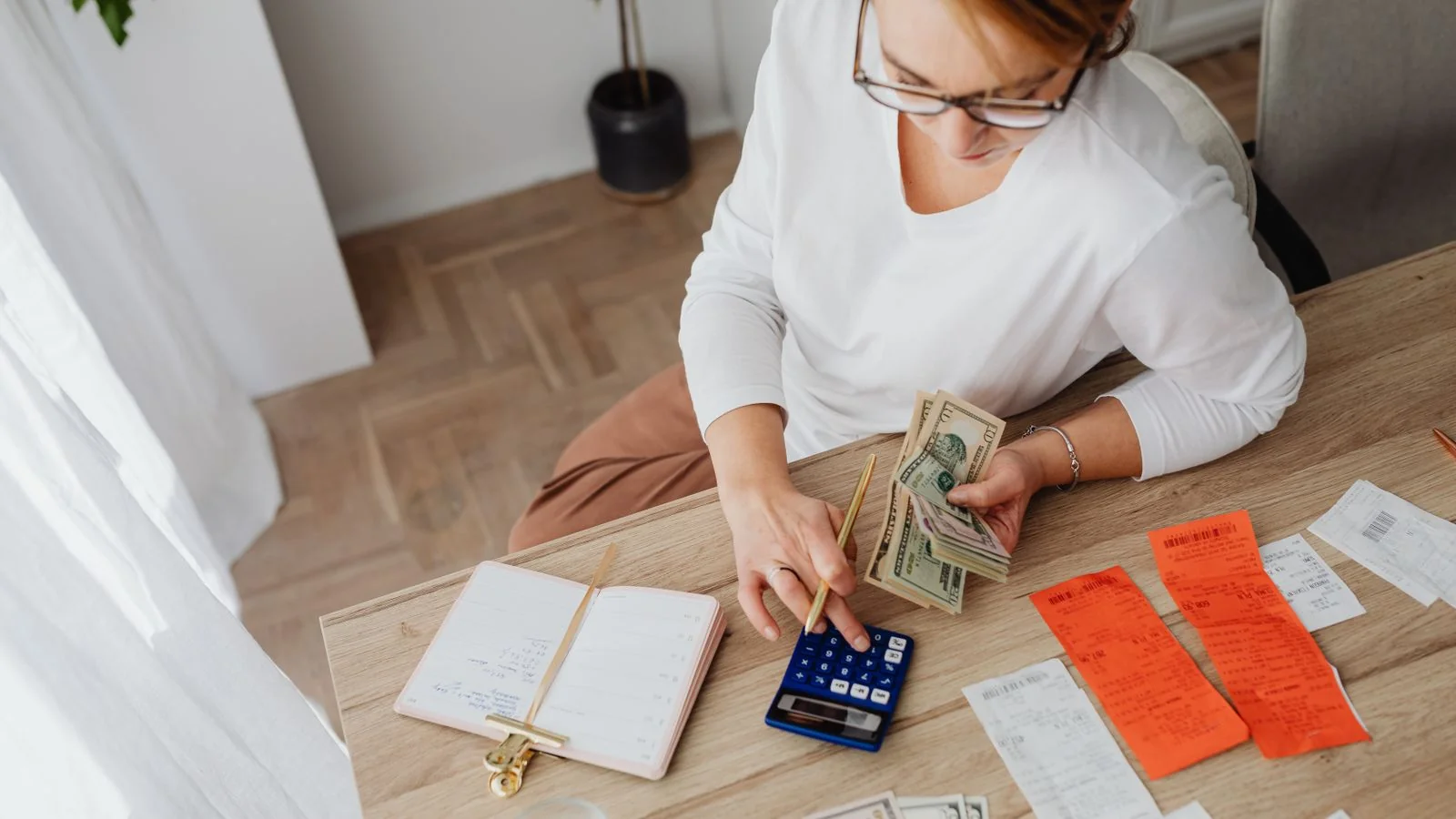 Woman working through household bills with a calculator, comparing subscription costs