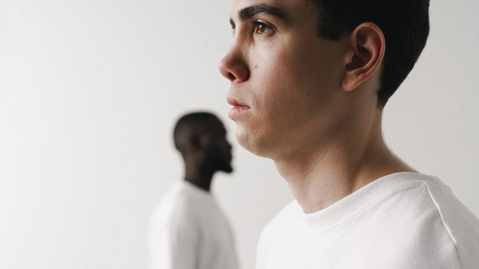 Two men in white shirts shown in side profile, a visual stand-in for one identity split in two