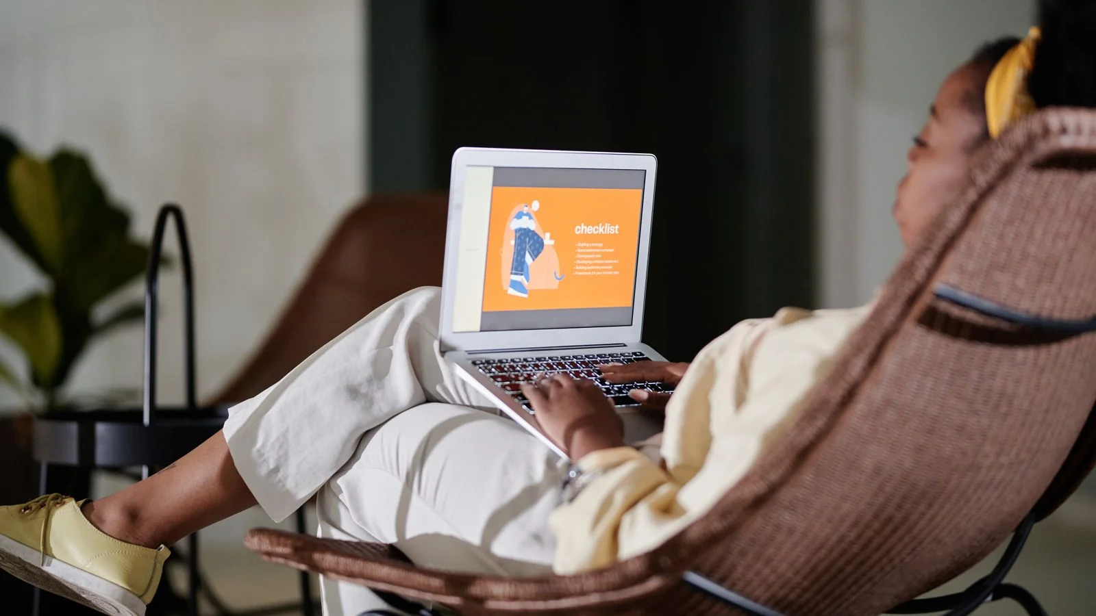 Person working on a laptop at home while reviewing a list of profiles and sources