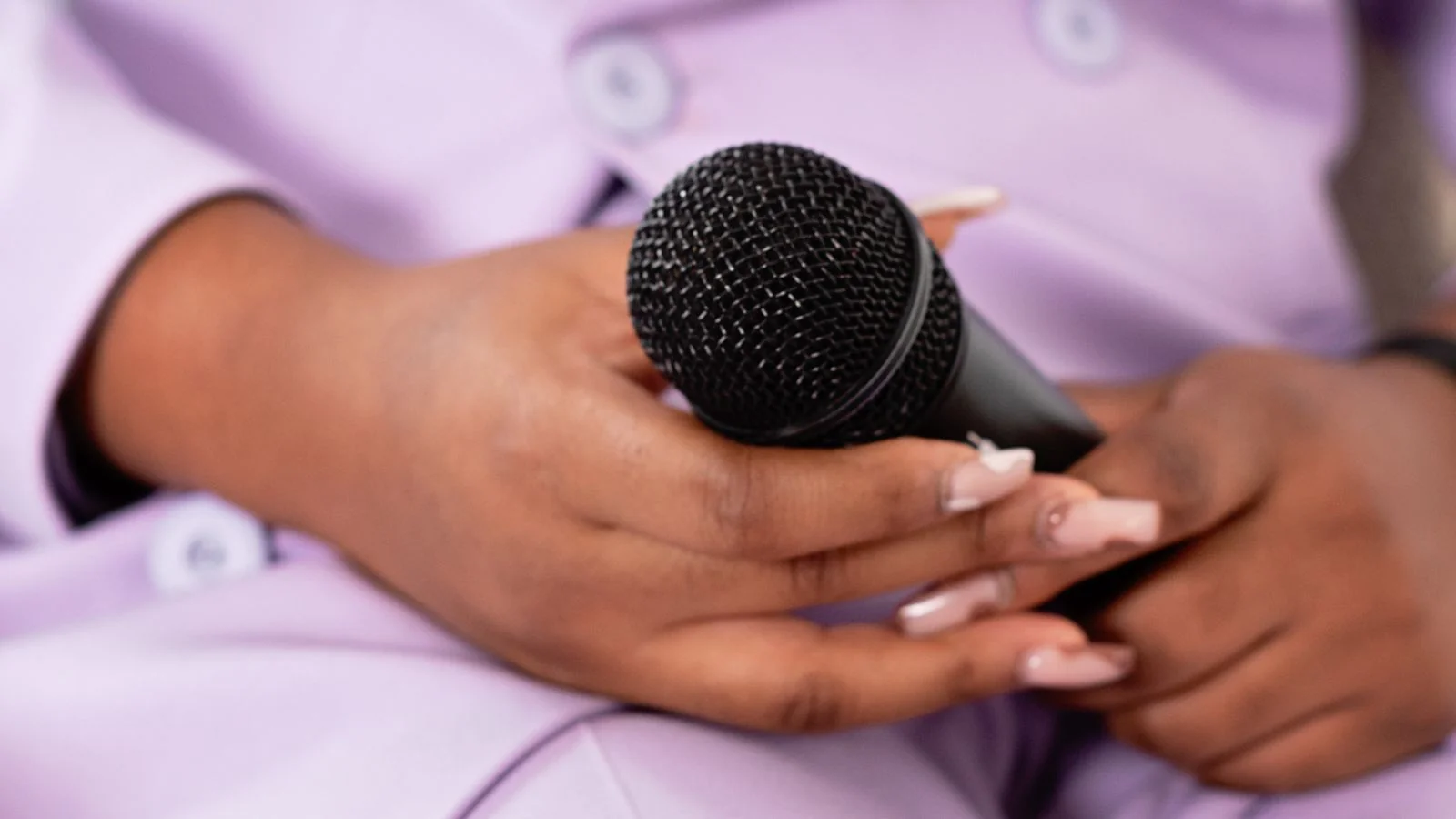 A hand holding a microphone, the third-party voice that makes earned coverage carry weight
