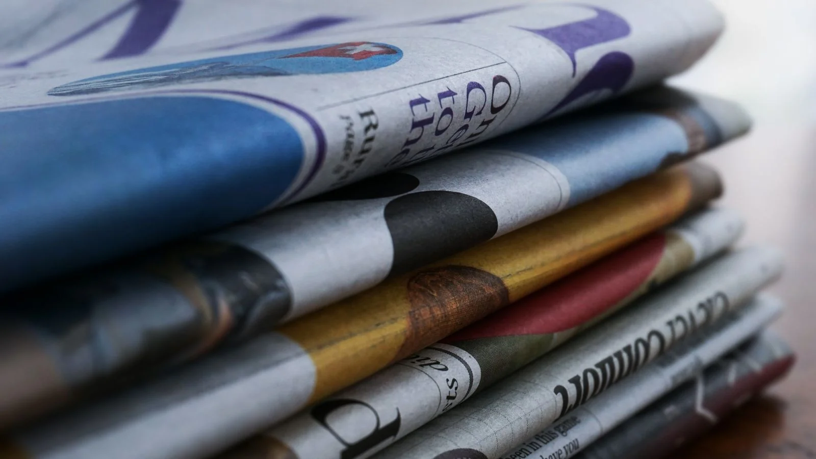 A close-up of stacked newspapers, the syndication volume both wires promise