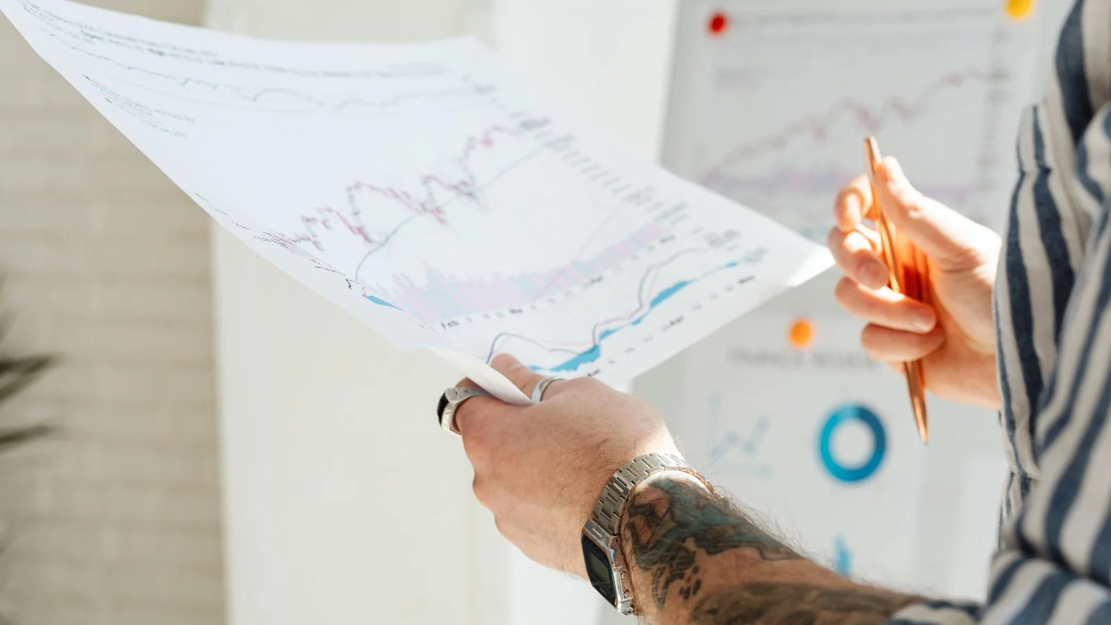 Hands holding printed financial charts, the close reading that benchmark numbers deserve