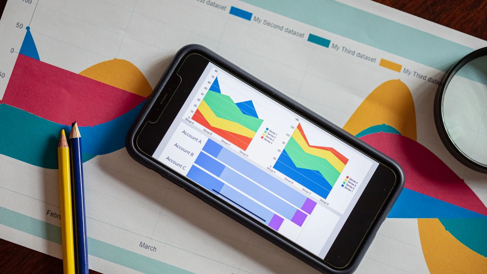 Smartphone displaying colourful charts over printed graphs, the kind of figure that needs its provenance checked
