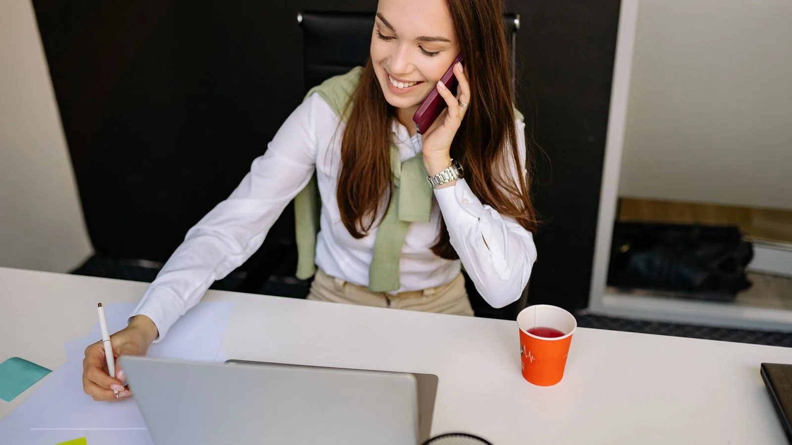 Woman working with a phone and laptop at her desk, the individual channel these studies keep measuring against brand accounts