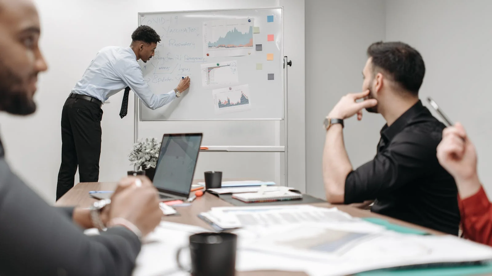 Colleagues collaborating around a meeting room table reviewing notes, the team scene the careers page should describe in 60 seconds of plain language.