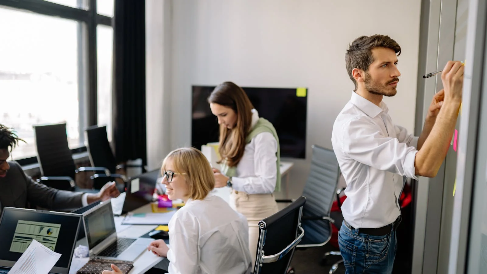 A team meeting in a modern office working through a project together, the daily texture the offer narrative should accurately describe.
