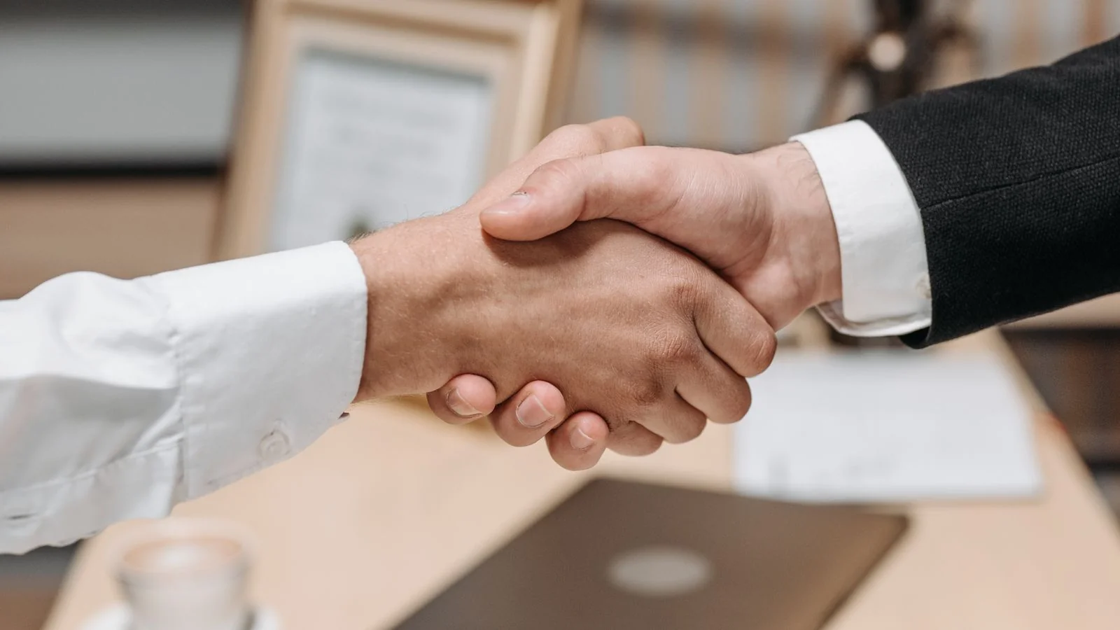 A close-up handshake between two professionals, the trust that both an exclusive and an embargo are built on