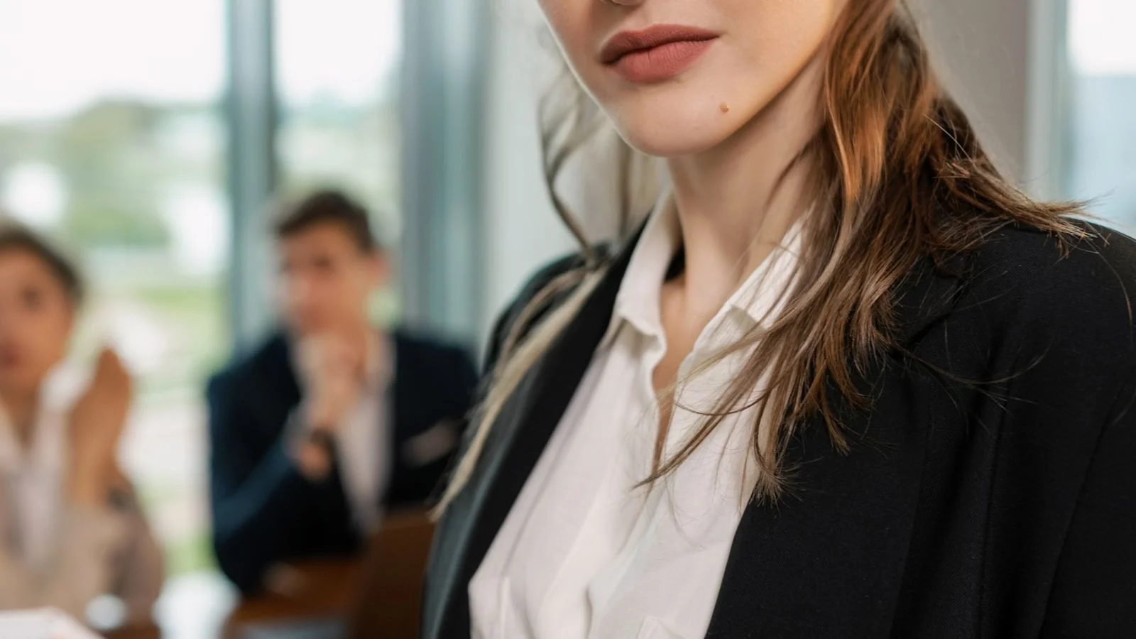A confident businesswoman holding a notepad in a meeting, demonstrating the composed authority of gravitas