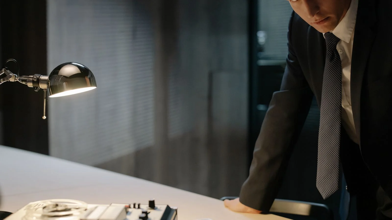 A detective examining evidence under a lamp, the documentation a platform report needs