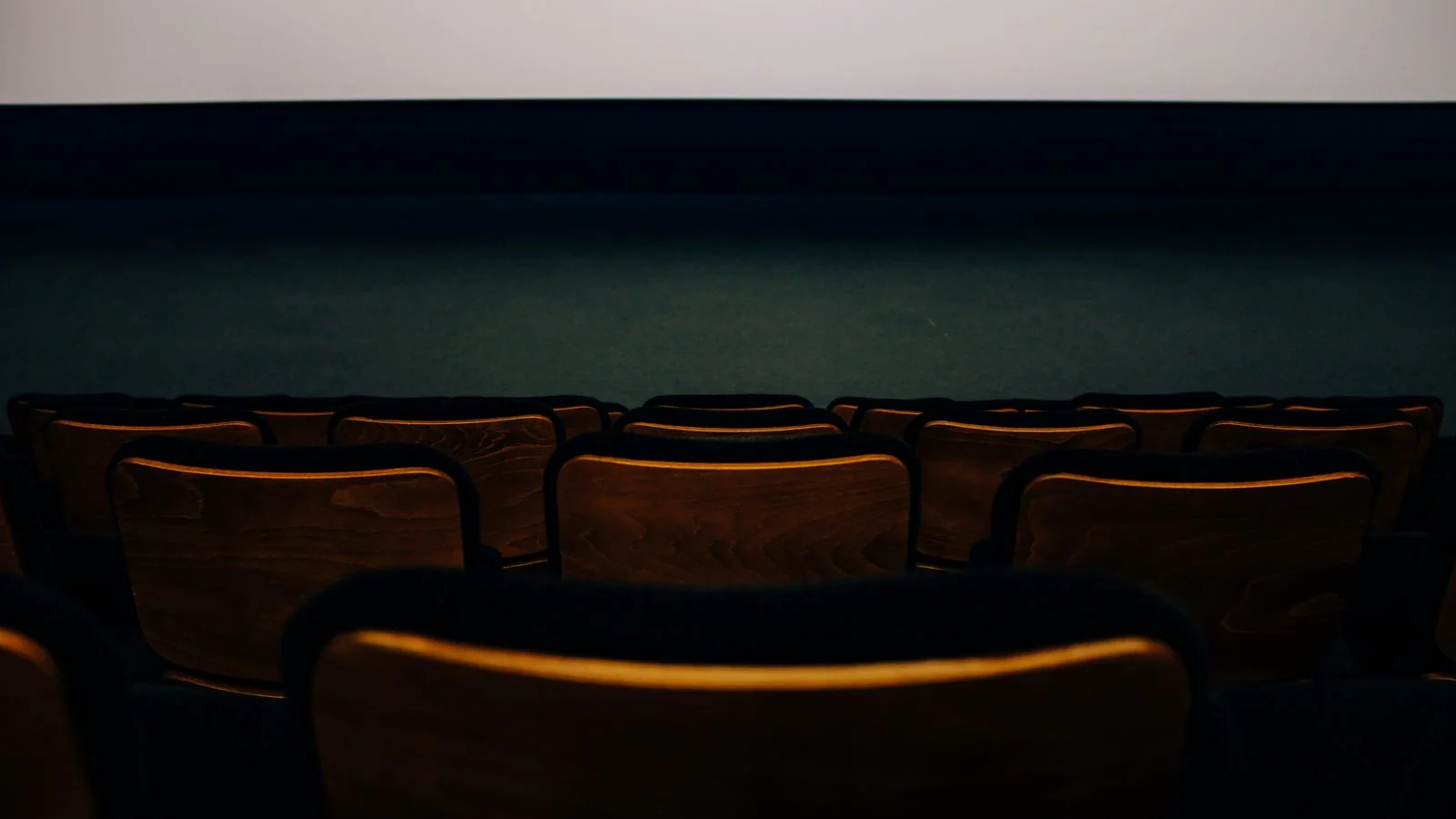 Empty auditorium with wooden seats facing a blank screen before a film premiere