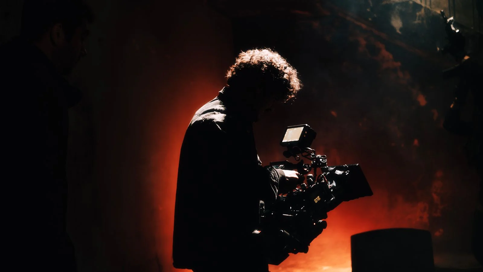 Cameraman filming in warm backlight, capturing footage for a film press kit