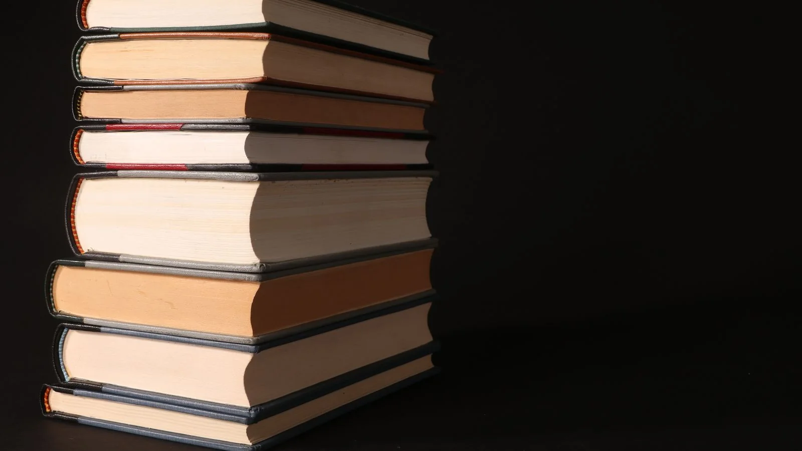 Stack of books photographed on a dark surface, representing the pool of sources an AI Overview draws its answer from