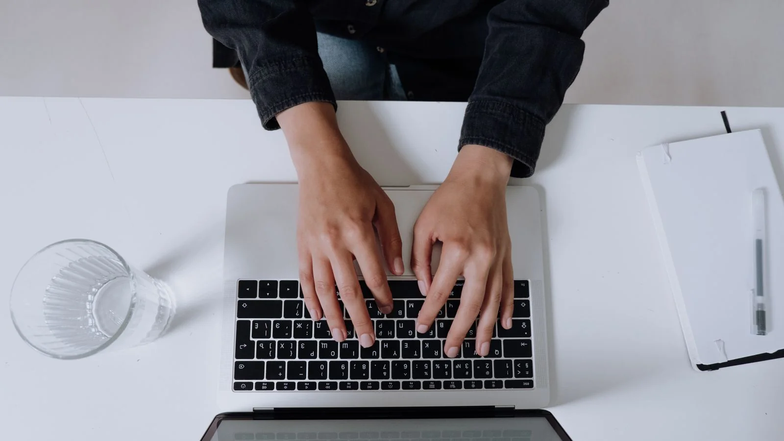 Hands typing on a laptop keyboard from above, the first step of every name search