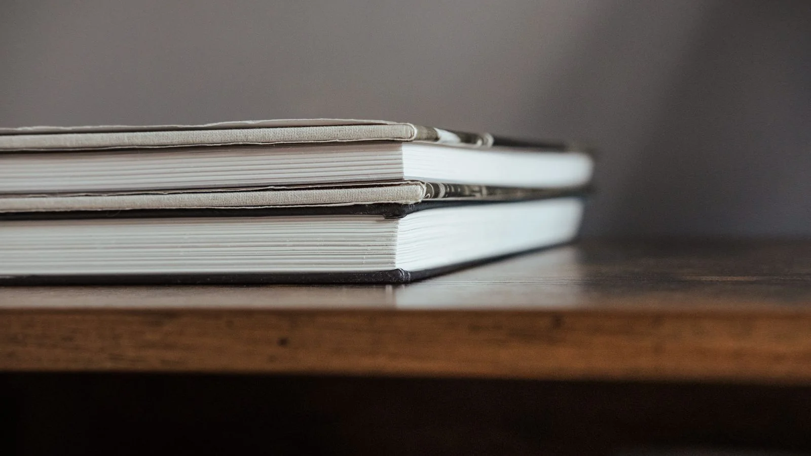 A pile of hardcover books on a wooden shelf, the catalog an author entity is built from
