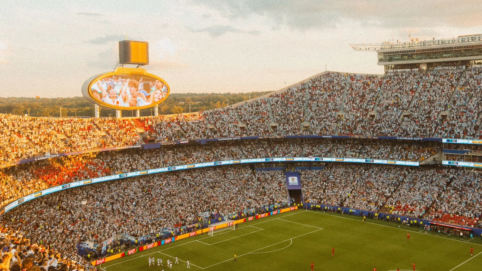 Packed stadium seen from above during a match at sunset