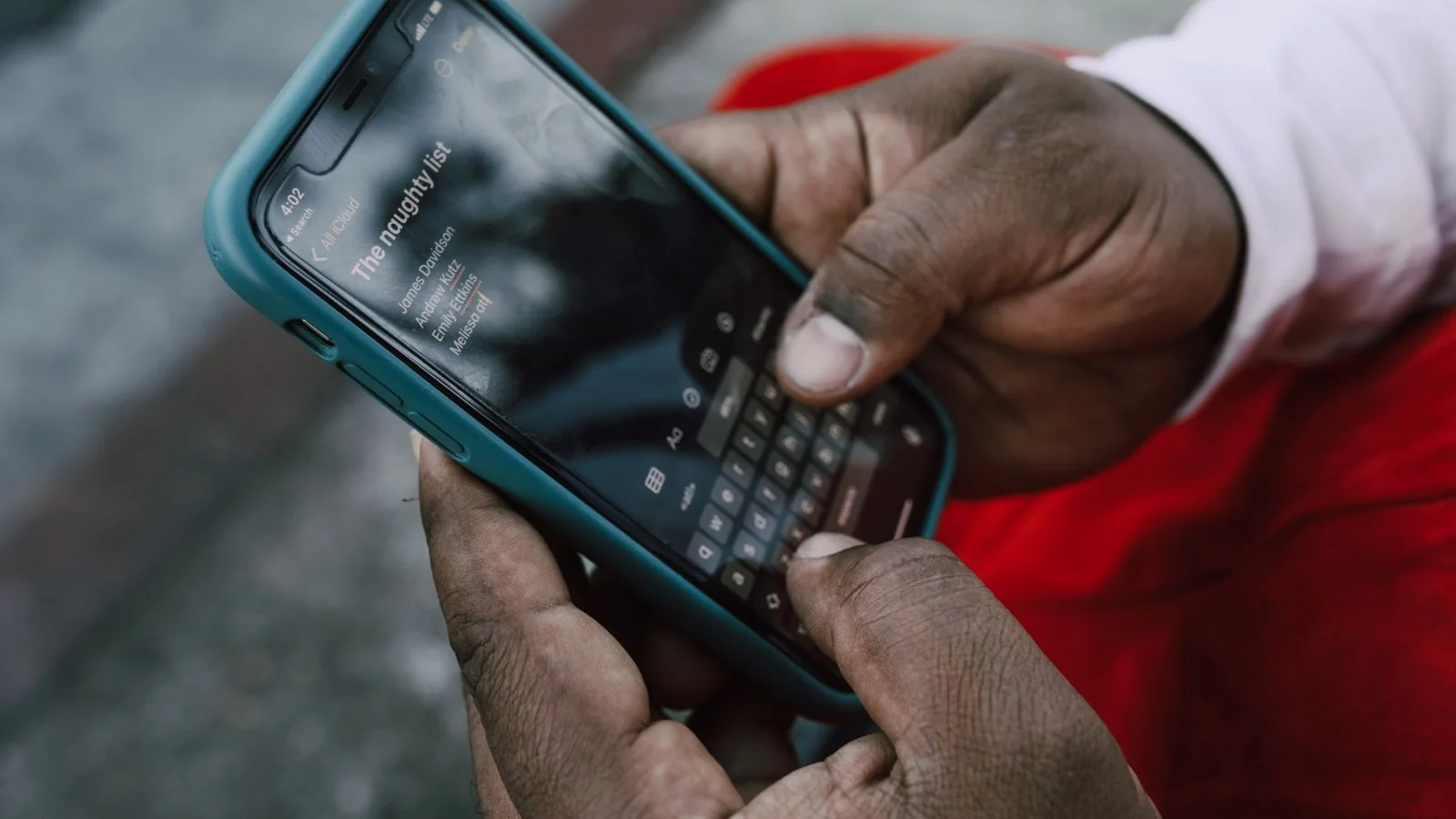 Close-up of a person typing a name into a smartphone search field