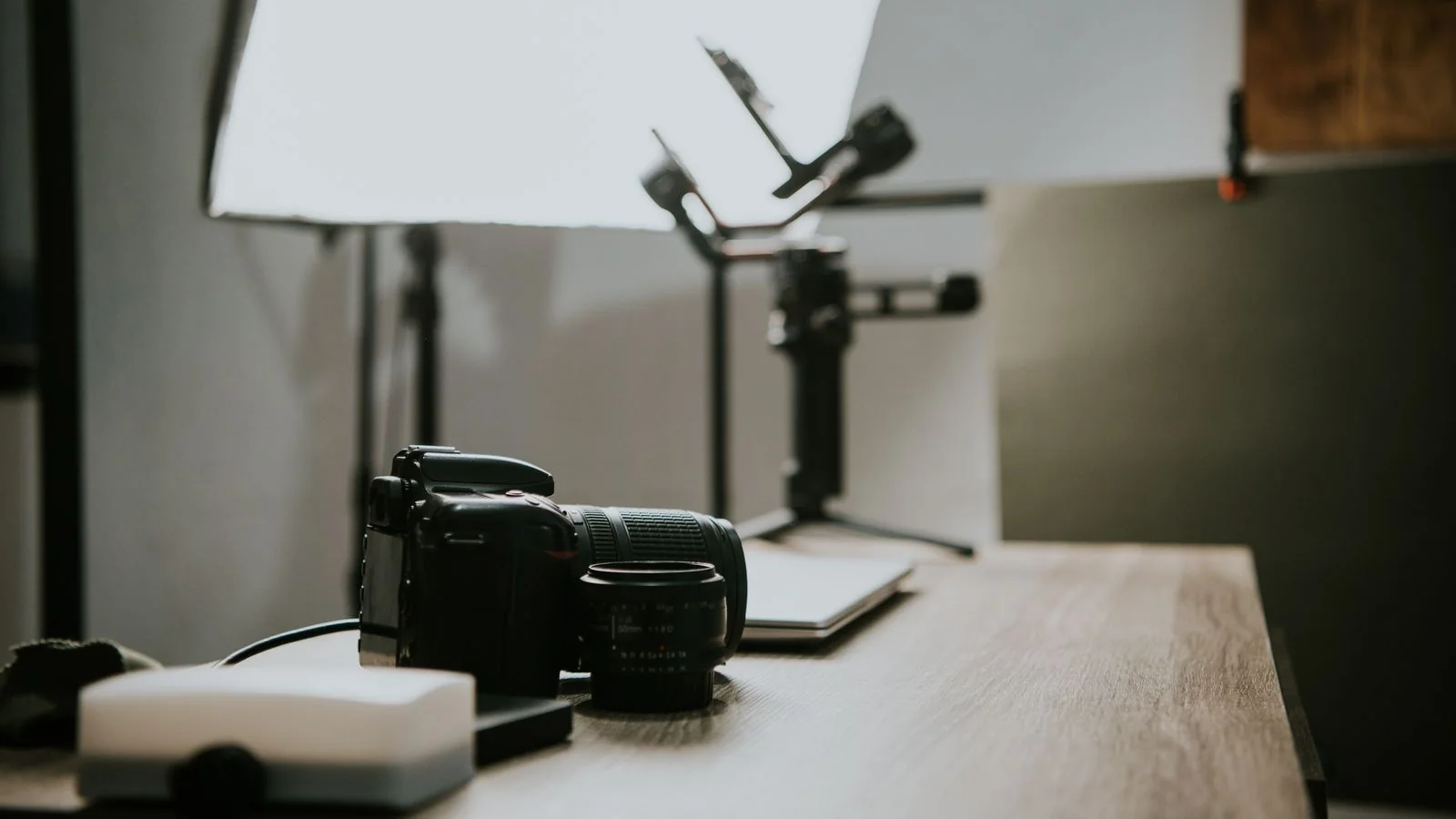 Camera lens resting on a wooden table, the tool whose output rarely carries its maker's name