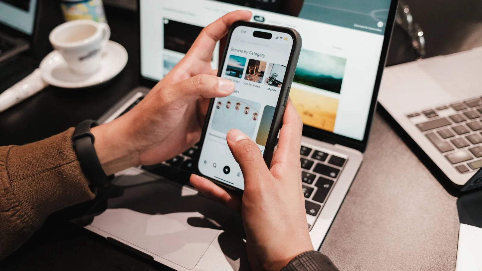 Hands using a smartphone over a laptop, the search that tells a podcaster whether Google has resolved them yet