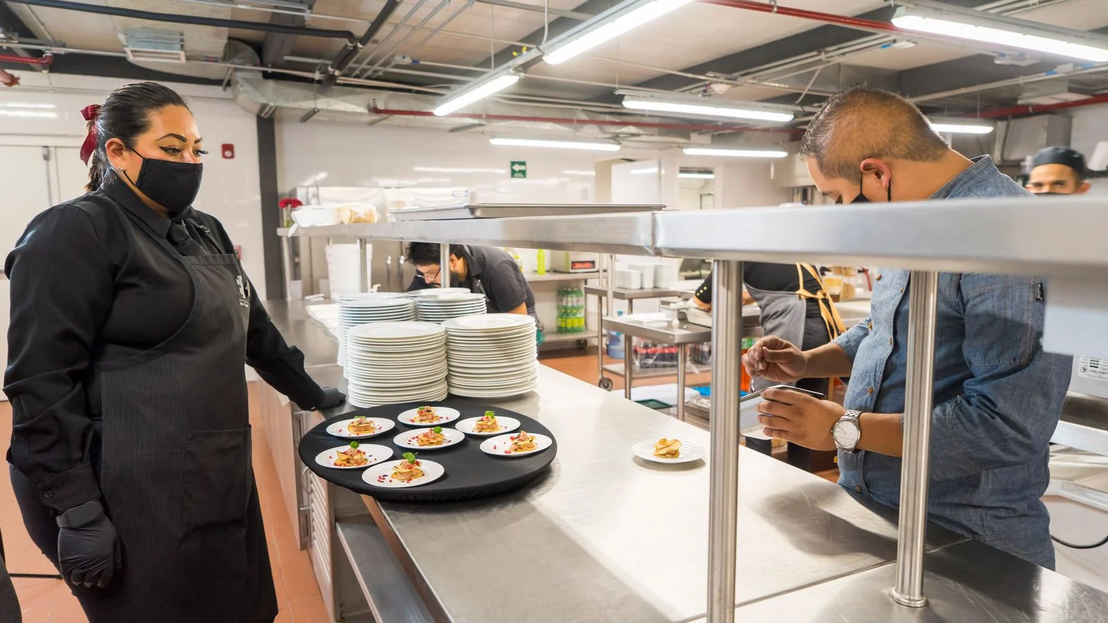 Chefs plating dishes in a busy kitchen, the operation a panel eventually describes