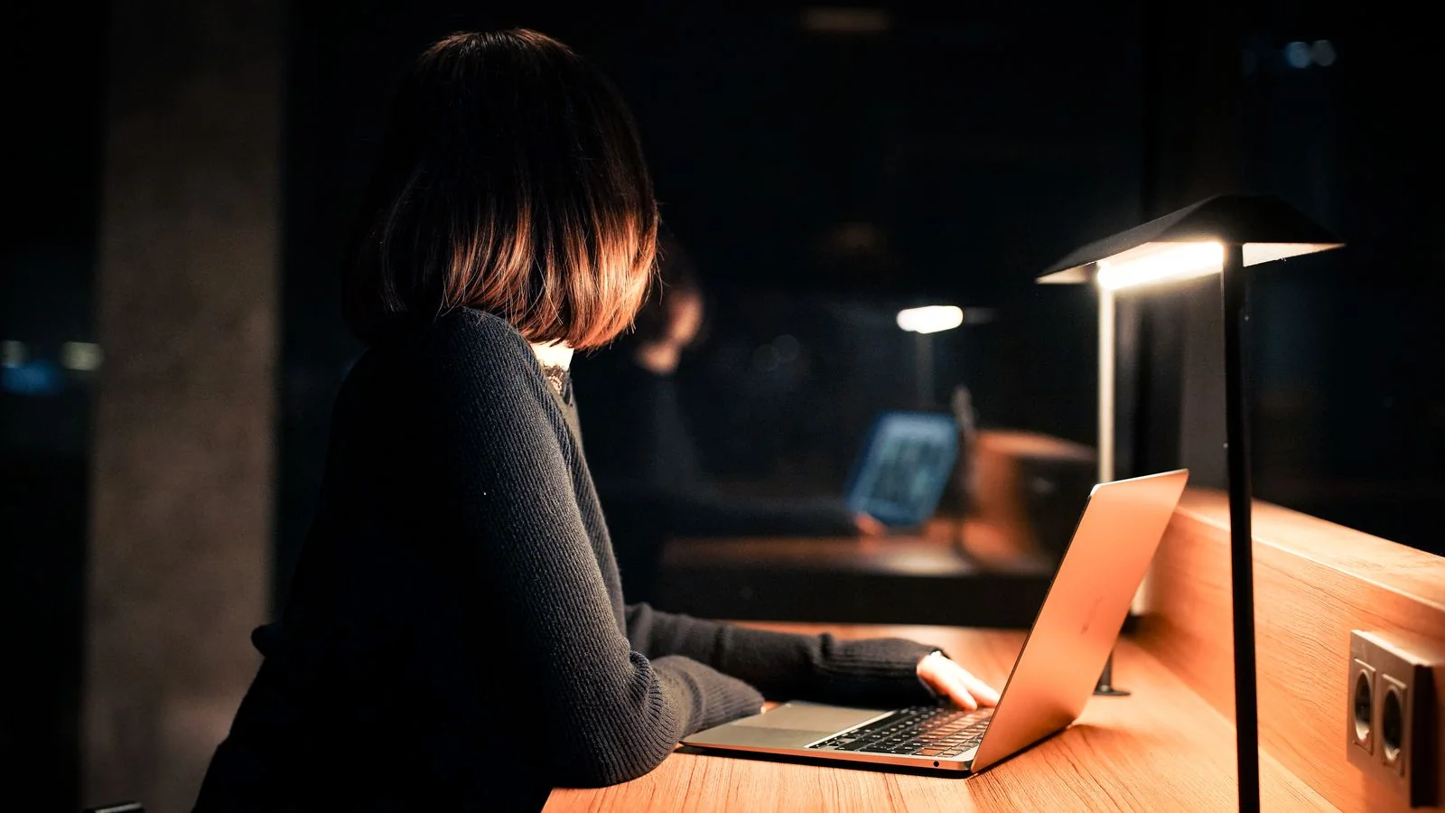Woman working at a laptop under warm light at night, running the kind of name audit this step requires
