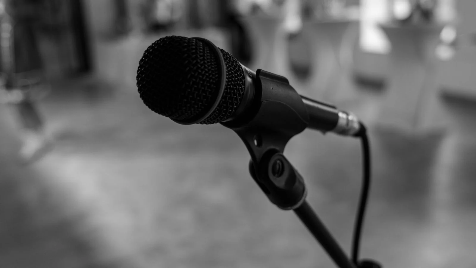 Grayscale close-up of a stage microphone, the stage-evidence corner of the triangle