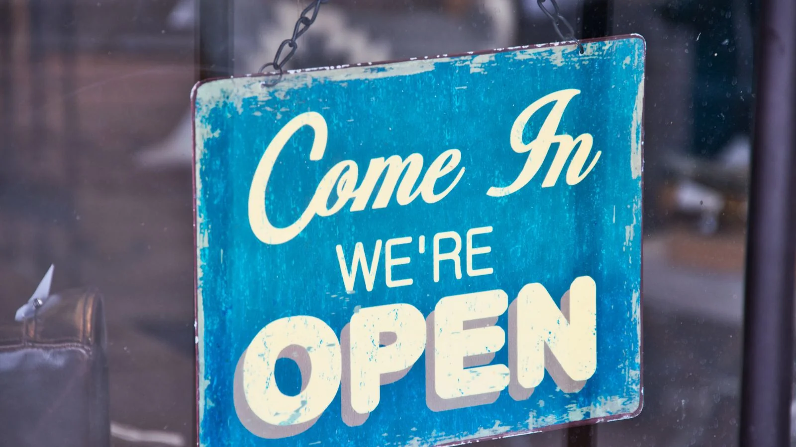 Blue open sign hanging on a shop glass door, the kind of local business a review score decides for