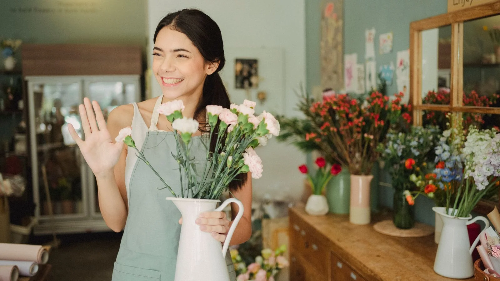 Shop owner smiling and waving from behind the counter of a newly opened florist