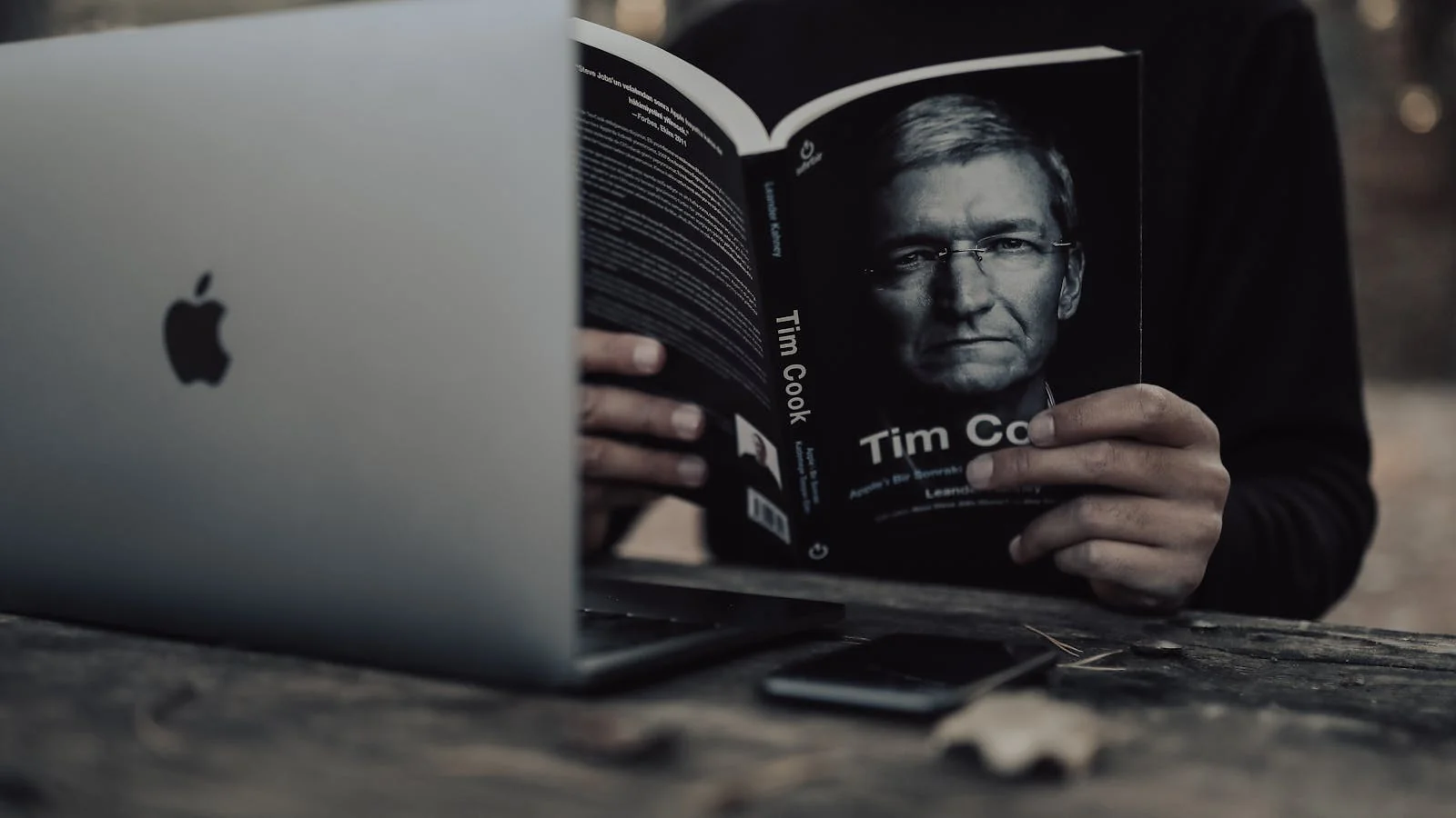 Reader cross-checking a book passage against a laptop search result, the multi-source verification AI mimics