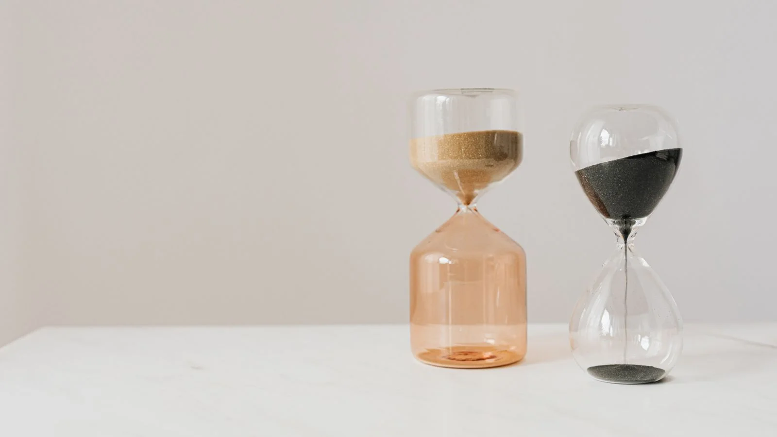 Hourglasses with pouring sand on a white table, a reminder that knowledge panels run on time