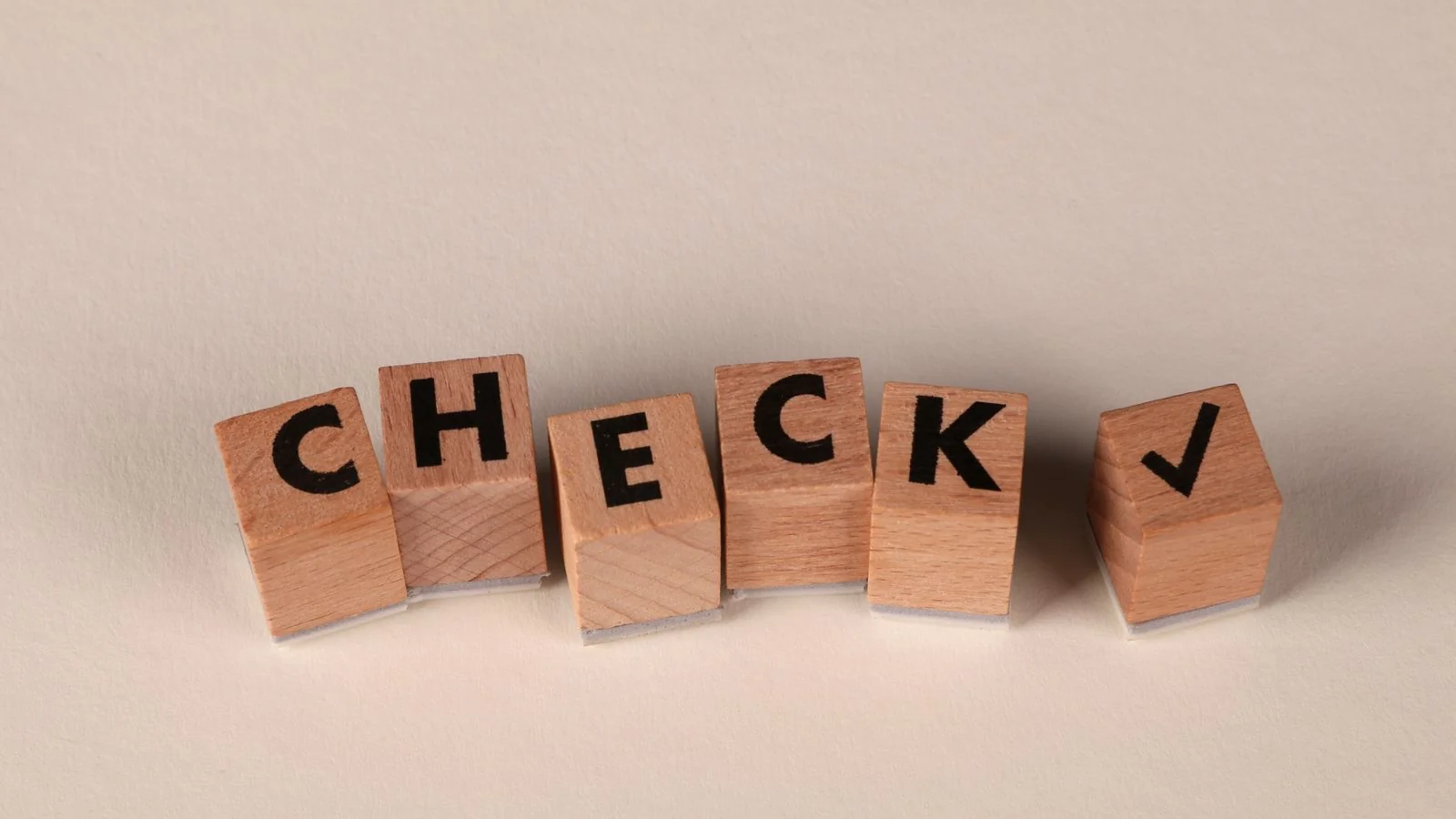 Wooden blocks spelling CHECK beside a checkmark, the verification step where SearchGPT decides a source is safe to quote