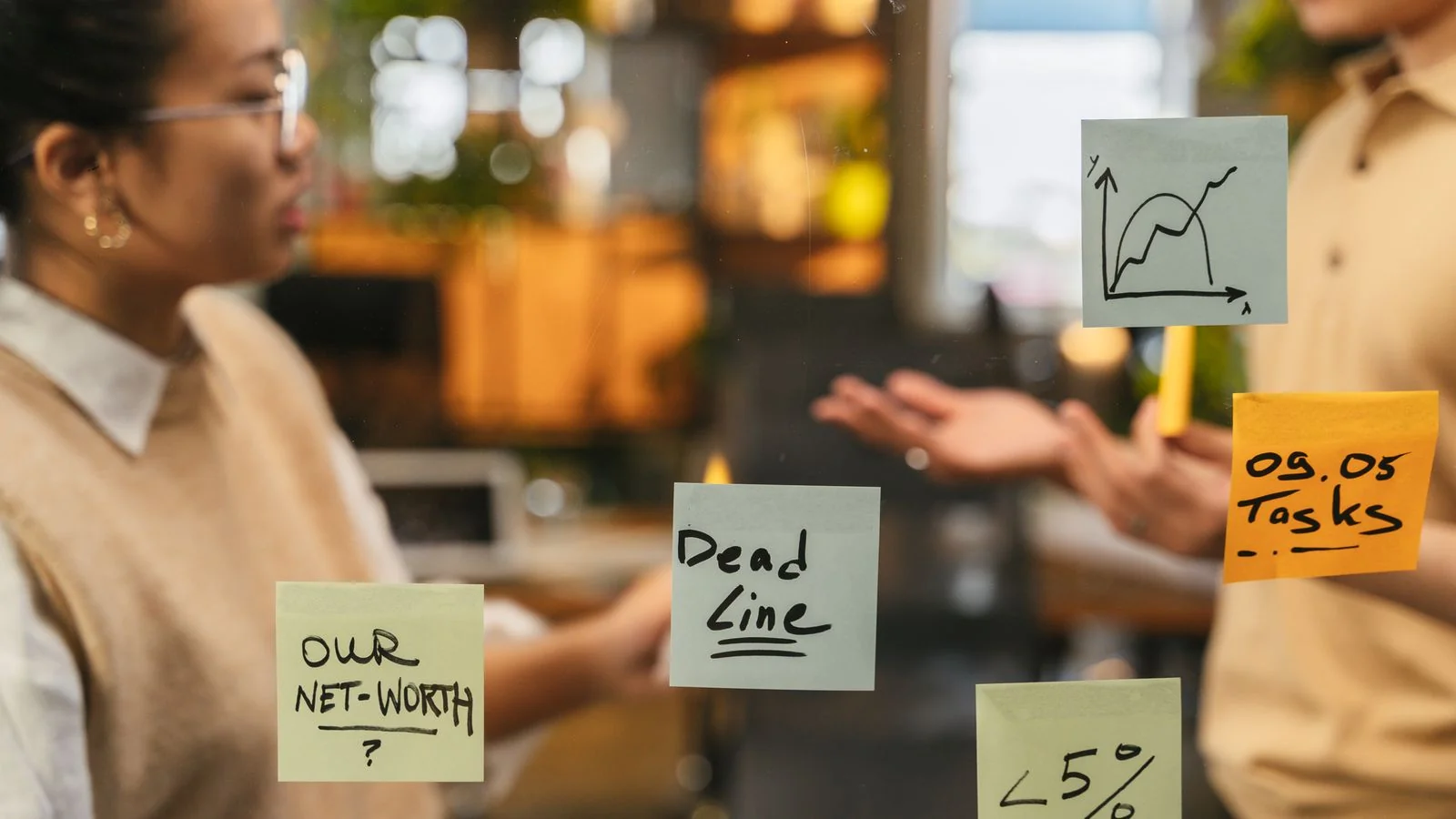 Sticky notes with handwritten questions on a glass wall, the raw material a citation-ready FAQ block is built from