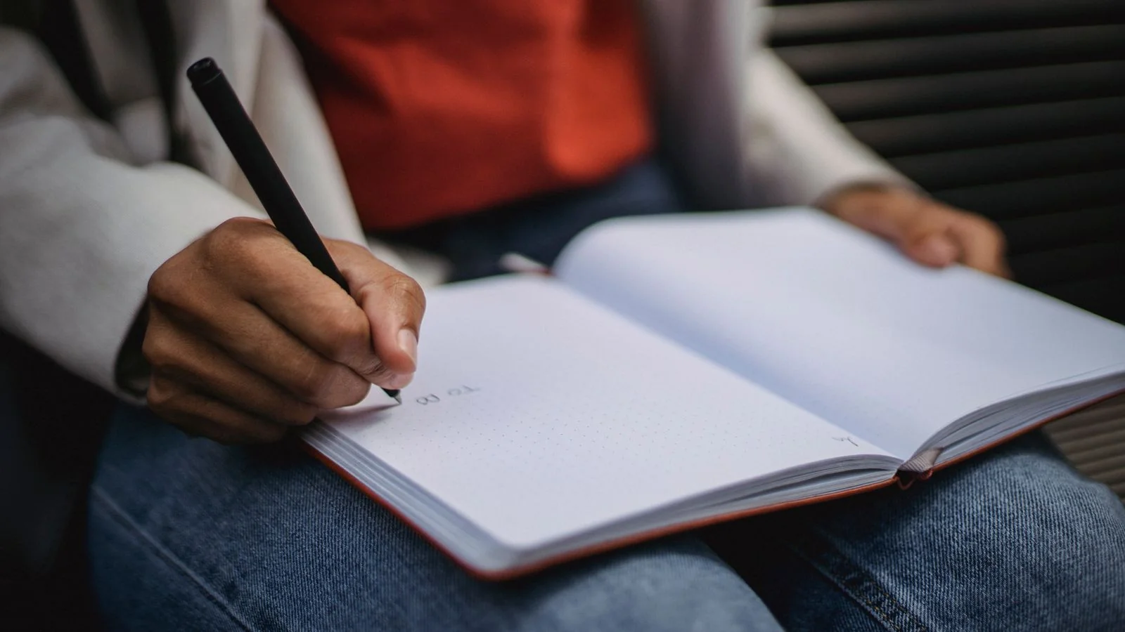 A person writing definitions in a notebook, the careful drafting a citable glossary entry demands