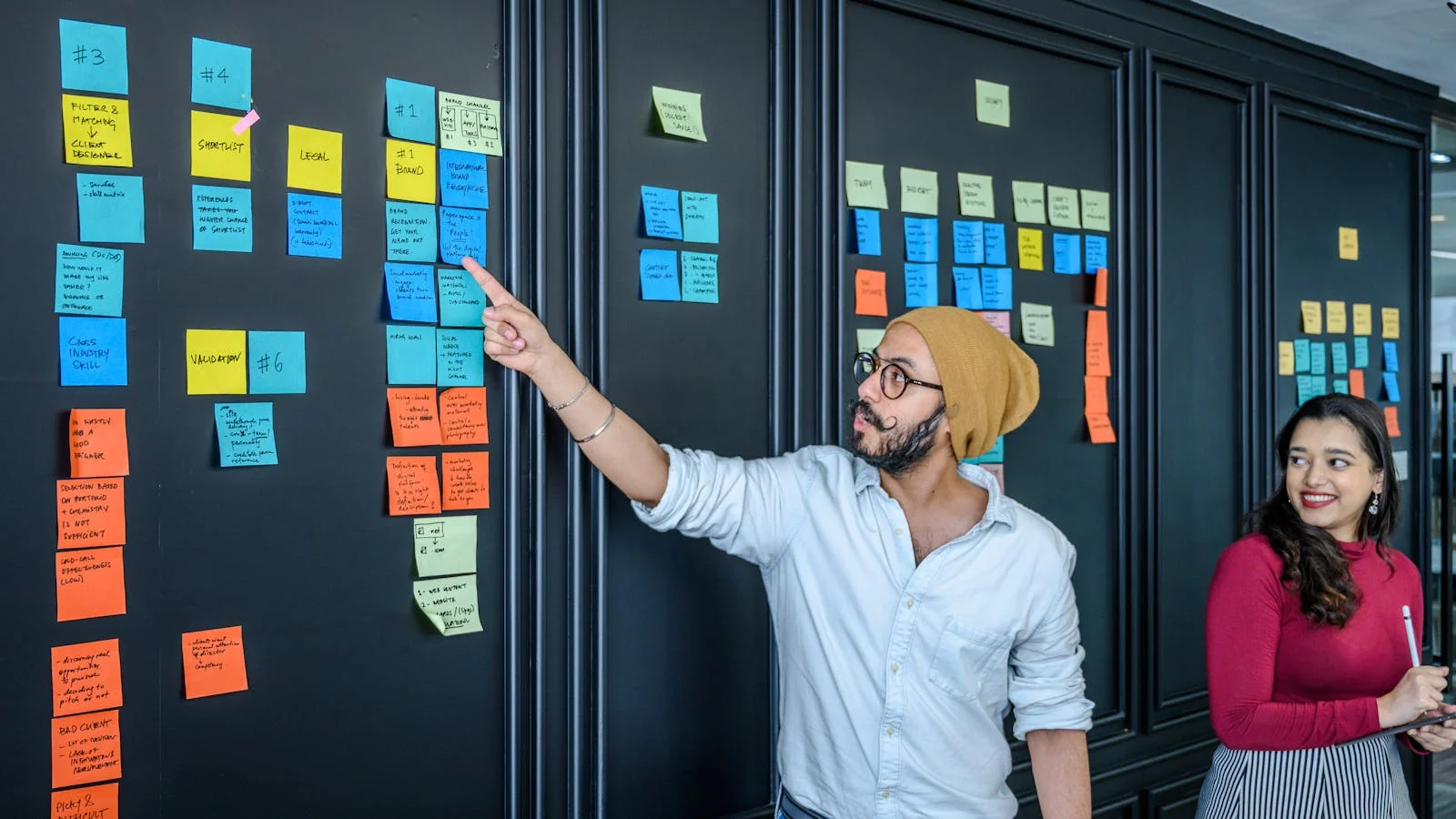 Team brainstorming press angles using colorful sticky notes on a glass wall during a PR positioning workshop