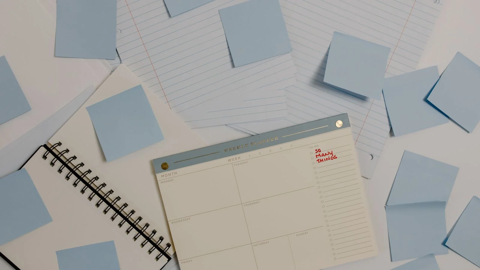 A planner, sticky notes, and lined paper laid out on a desk, the raw materials of a publishing plan
