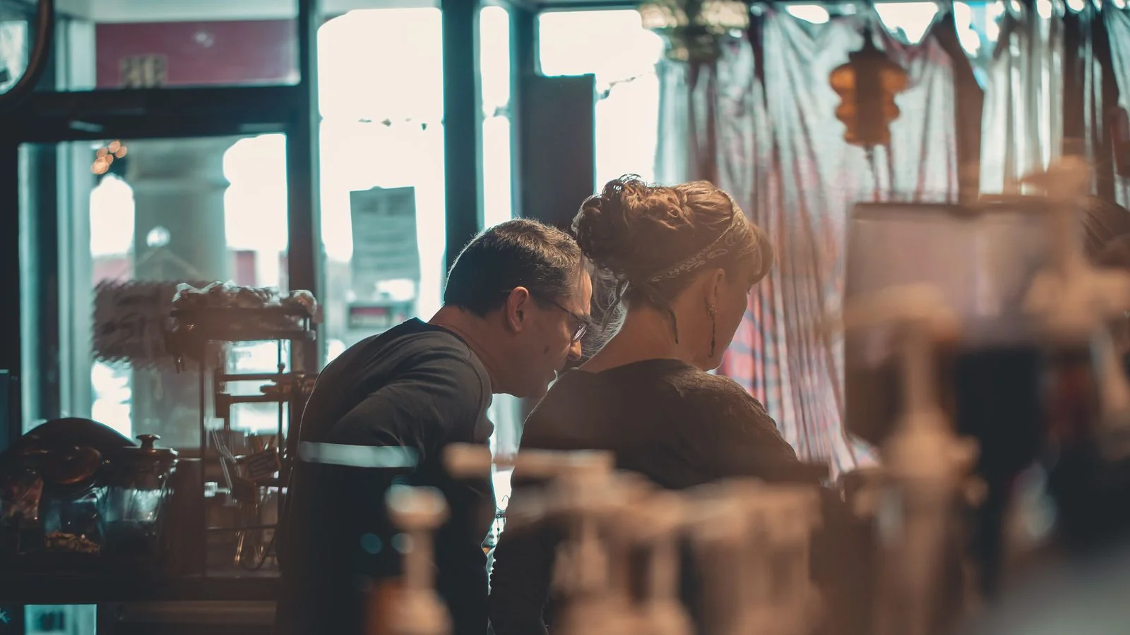 Two business owners in conversation inside a warm cafe interior, the kind of operator-to-operator referral network that compounds when pages are set up right.