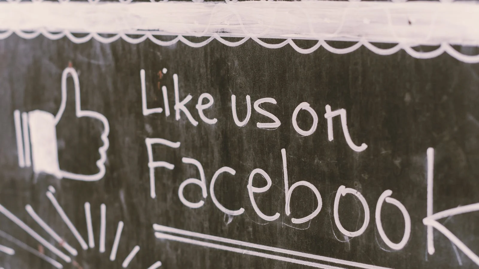 A chalkboard sign reading 'Like us on Facebook,' the old-school cue that still works when paired with a properly set-up page.