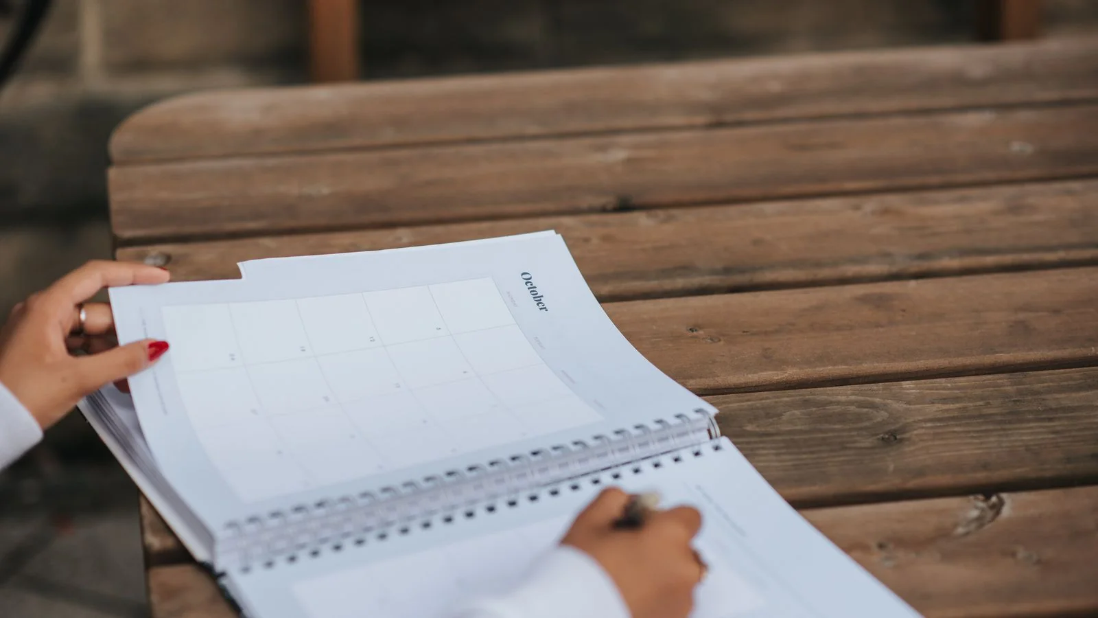 A woman writing planning notes in a notebook, mapping goals before filling a content calendar