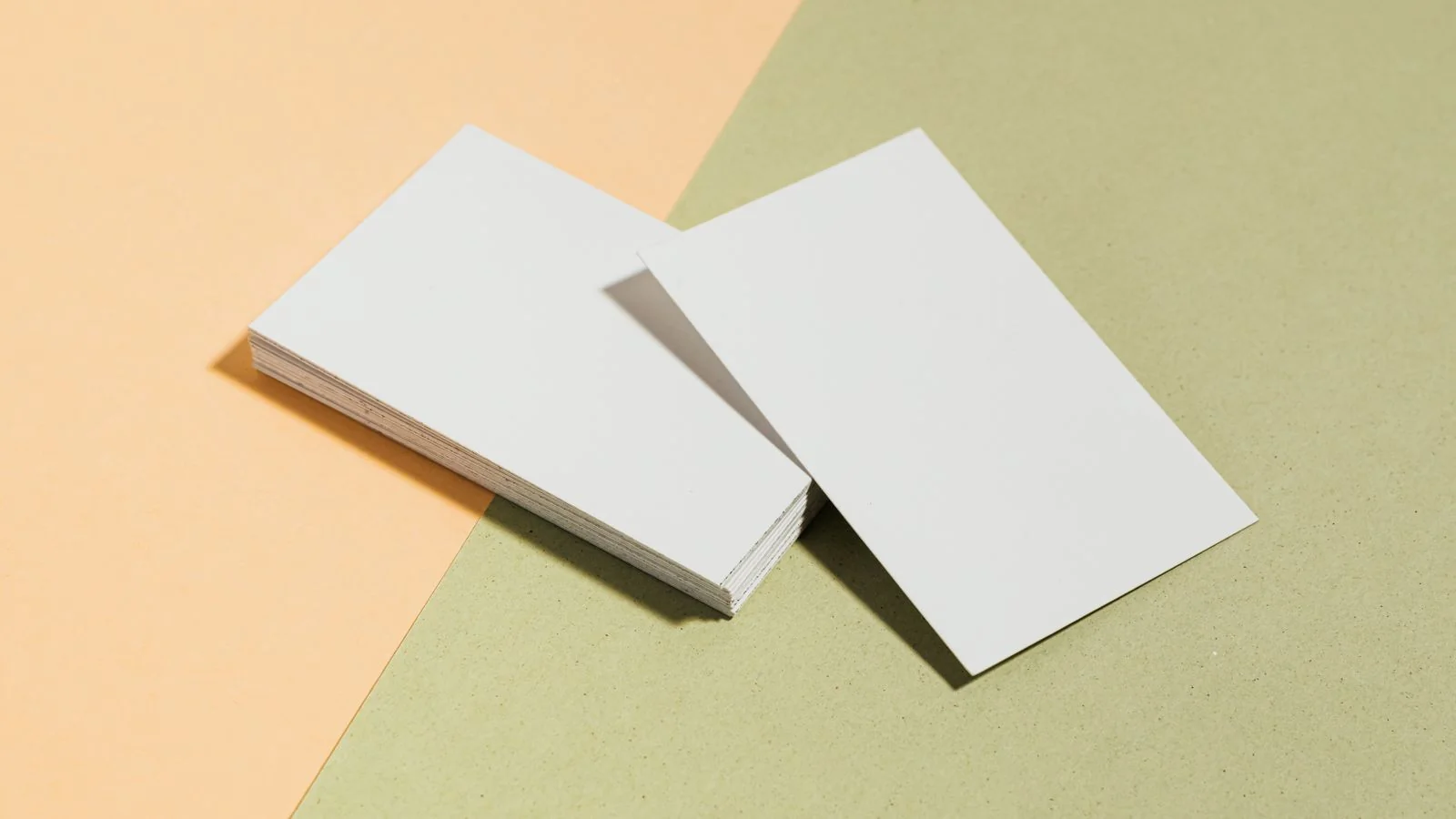 Stack of minimal business cards on a pastel surface awaiting a design