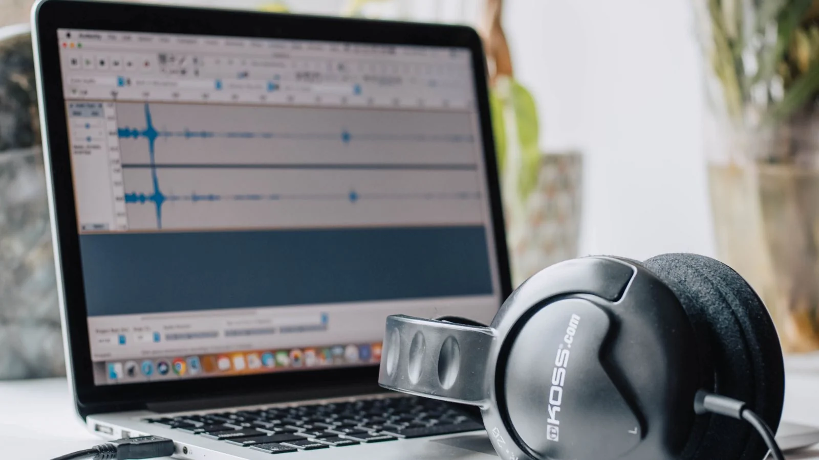 A laptop running audio editing software with headphones, where one episode becomes many assets